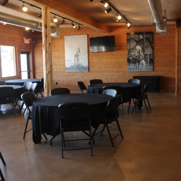 A rustic event space with wooden walls, black-draped tables, and Western-themed artwork at Meyer's Elgin Smokehouse.