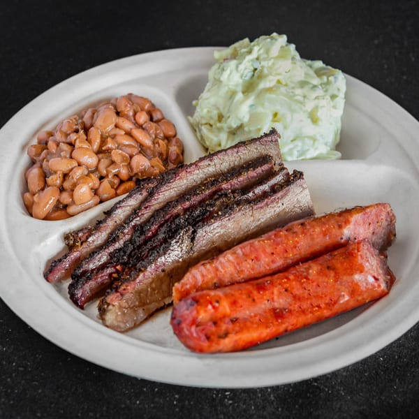 Meyer's Elgin Smokehouse BBQ plate with sliced brisket, sausage, baked beans, and potato salad.