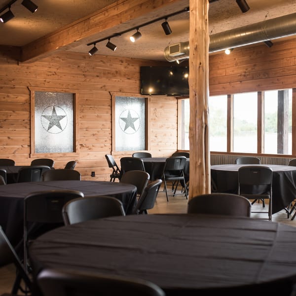 Meyer's Elgin Smokehouse event room with wood paneling, black-draped tables, and star-patterned windows.