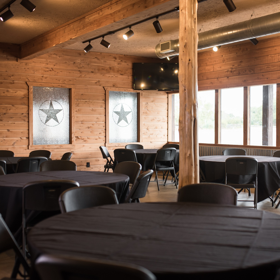 Meyer's Elgin Smokehouse event room with wood paneling, black-draped tables, and star-patterned windows.