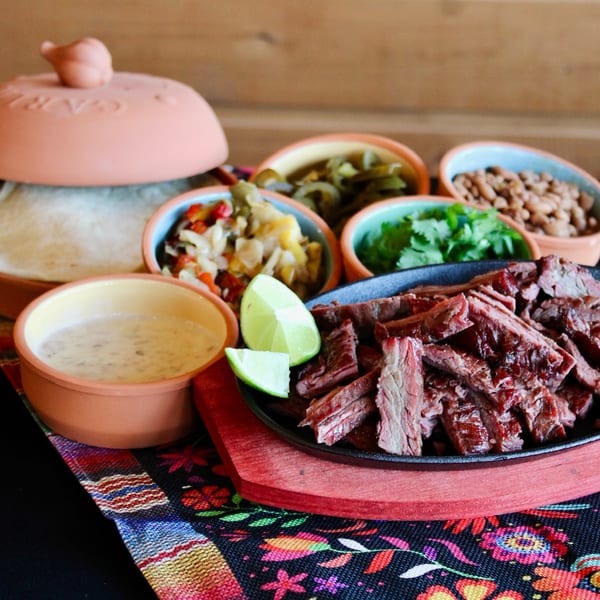 Meyer's Elgin Smokehouse sliced brisket with sides of beans, salsa, and tortillas.