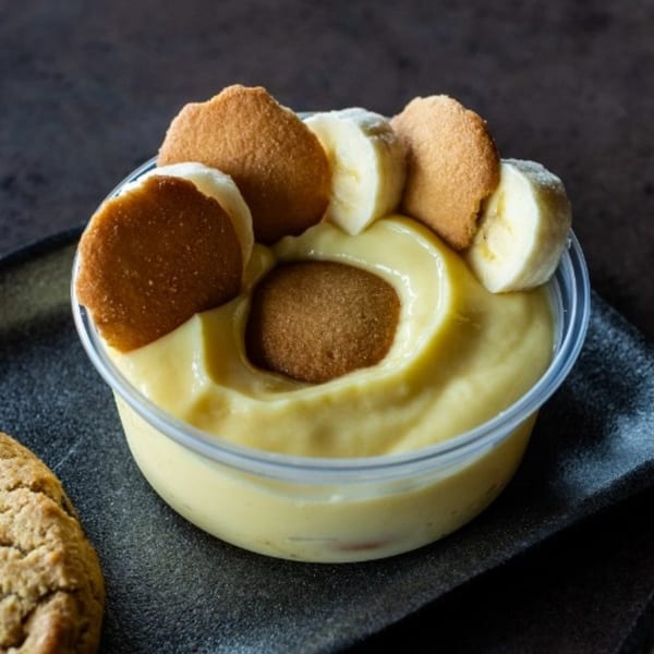 Meyer's Elgin Smokehouse banana pudding with vanilla wafers and fresh banana slices in a clear cup.