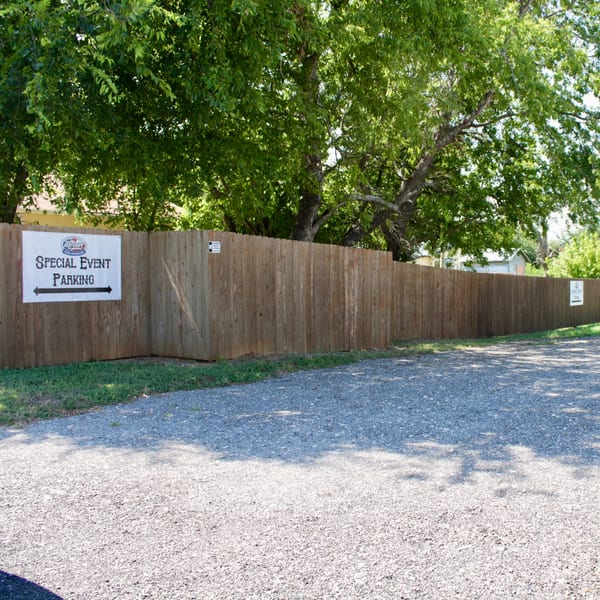 A Meyer's Elgin Smokehouse sign on a wooden fence directs to "Special Event Parking" in a gravel lot.